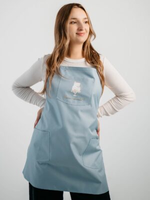 Fartuszek Comfort w kolorze dusty blue, widok z przodu, z logo klientki na kieszeni